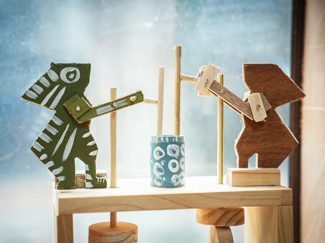 Figuras y piezas de juguetes de madera sin pintar apoyadas sobre un tablero de trabajo